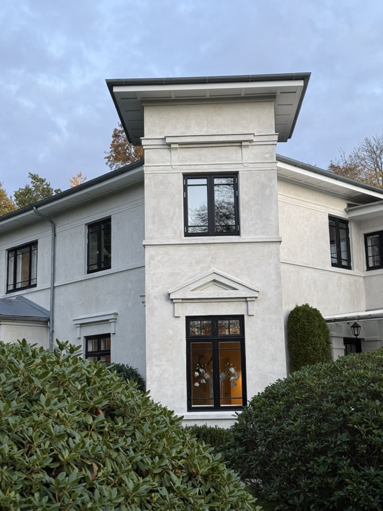 The residence's central tower with deep eaves, rising above rhododendrons